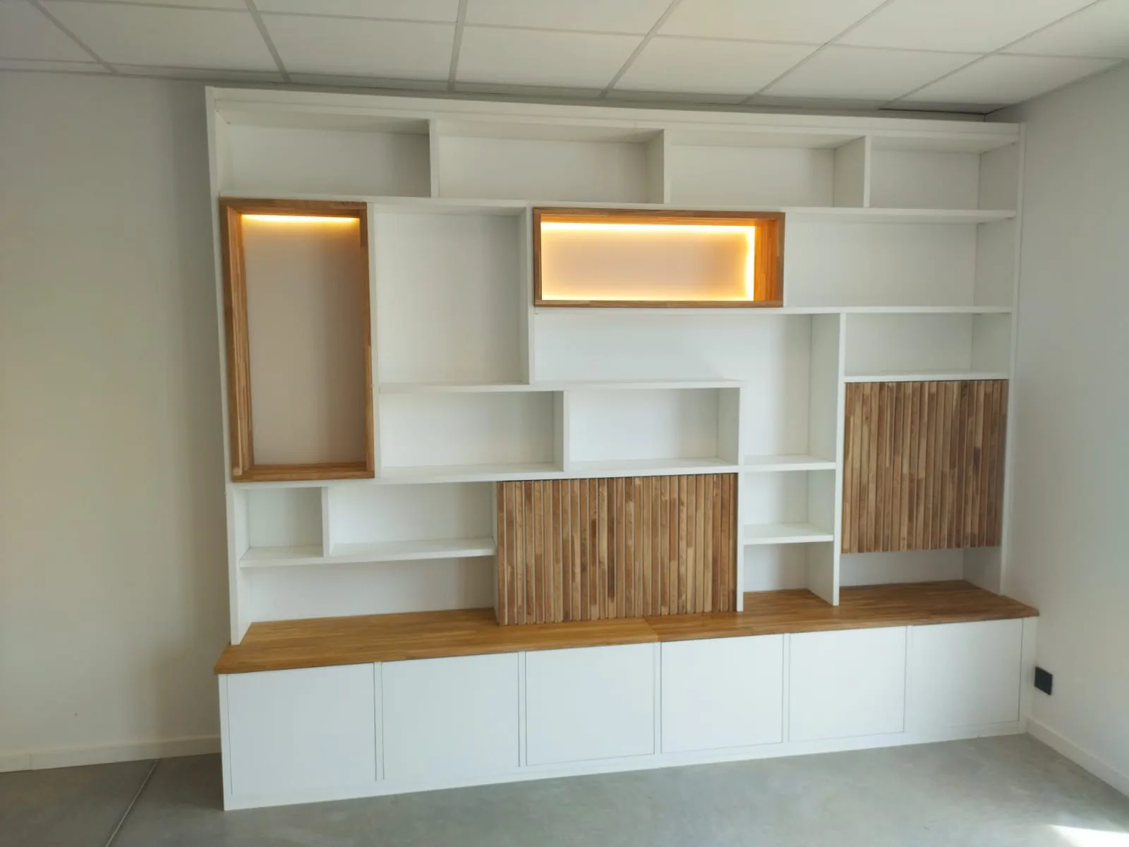 Meuble d'agencement blanc à niches chêne rétroéclairées, dans un espace professionnel