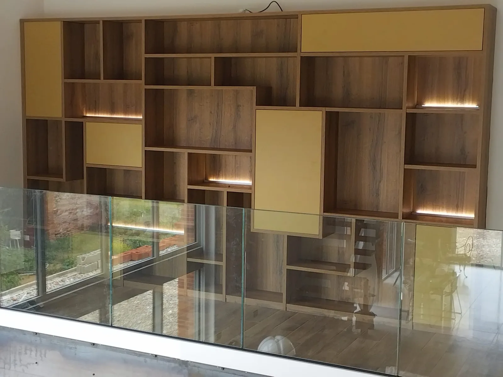 Agencement toute hauteur en bois et jaune avec niches éclairées