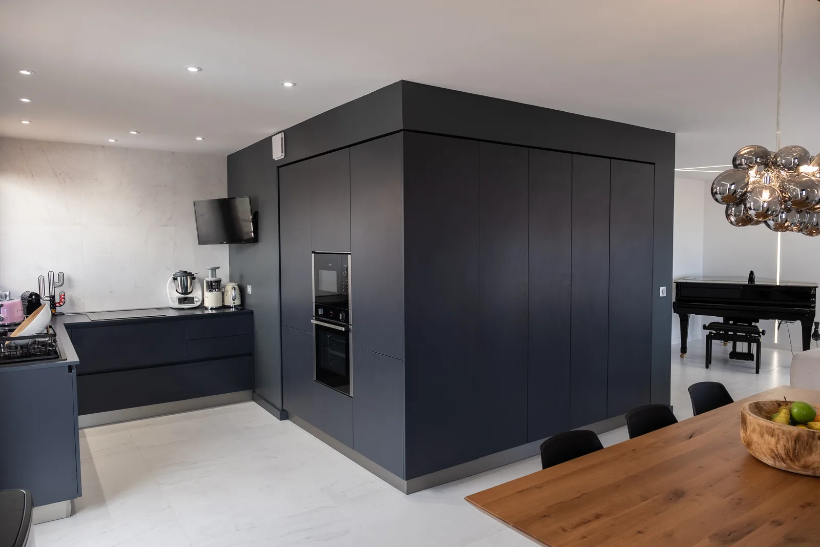 Bloc technique noir mat toute hauteur, façades sans poignée et angles vifs
